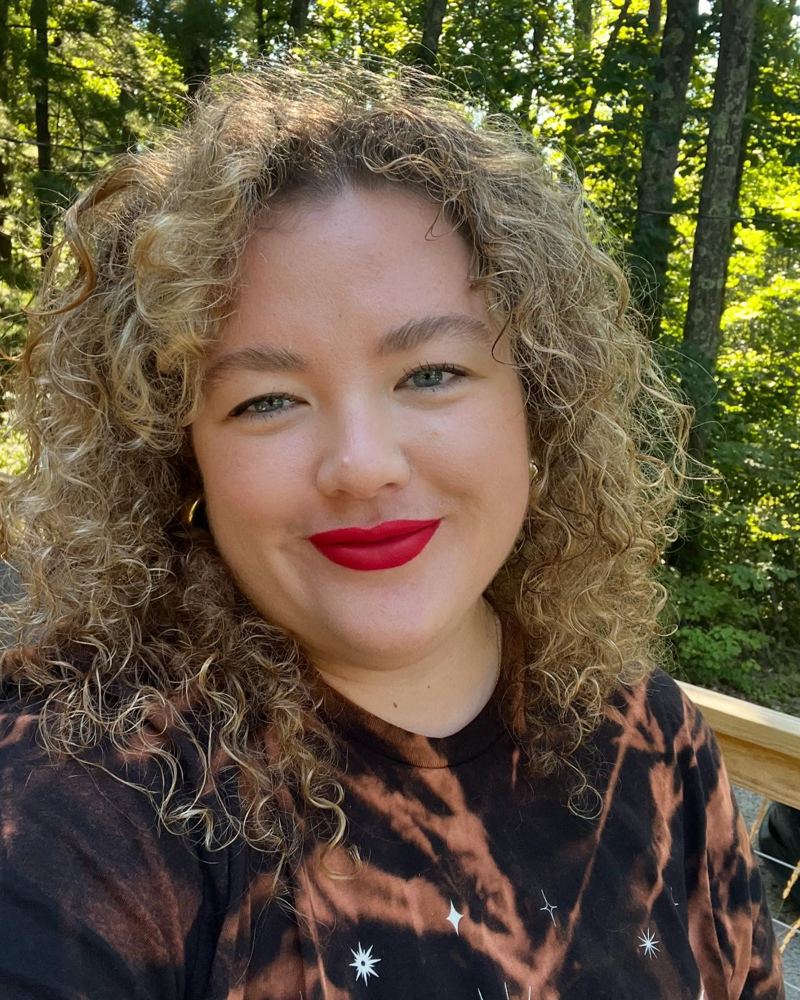 Jessica in red lipstick on a wooded deck
