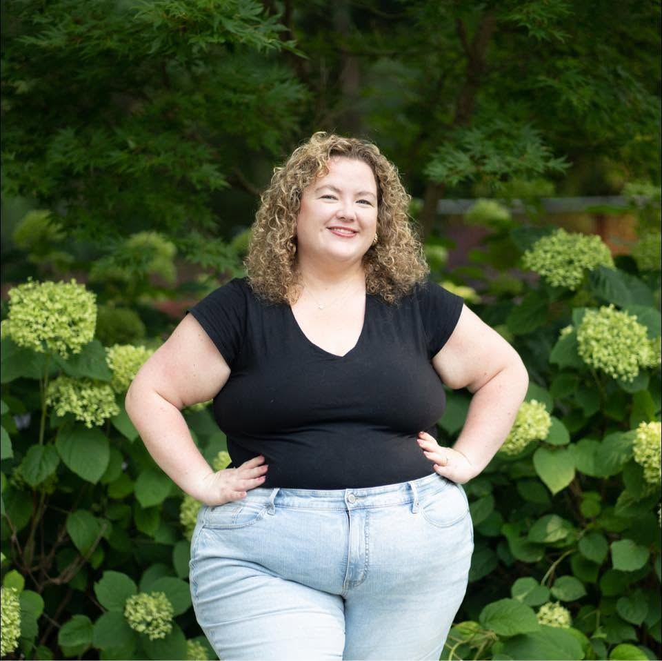 Jessica with hands on hips in front of hydrangeas